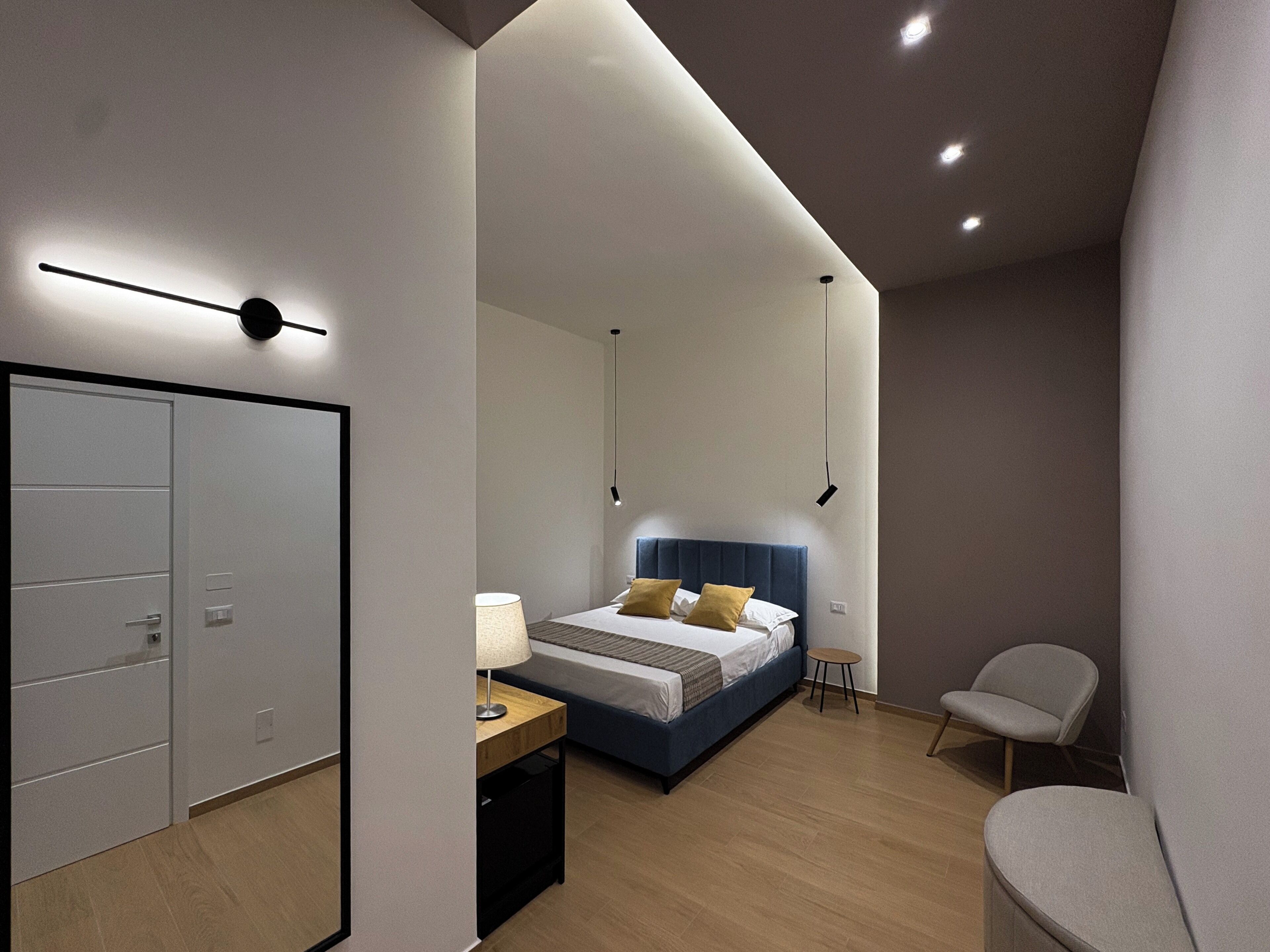 A modern bedroom with a bed, bedside table, chair, and wardrobe.