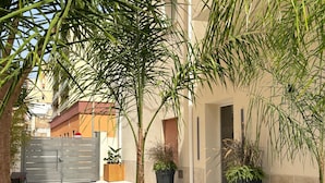 Une cour avec un banc, des plantes en pot et une porte.