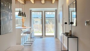 A spacious hallway with wooden flooring, a large window with a view of a backyard, and a modern console table with a mirror.
