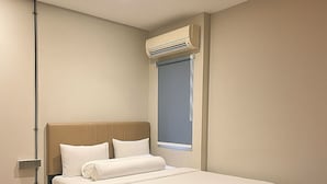 A modern hotel room with a single bed, a window with a view, and an air conditioning unit. - Anders Permata Millenium (Curug)