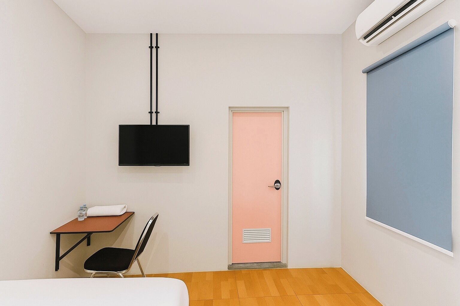 A room with a bed, a desk, a chair, a television, a door, and a window.
