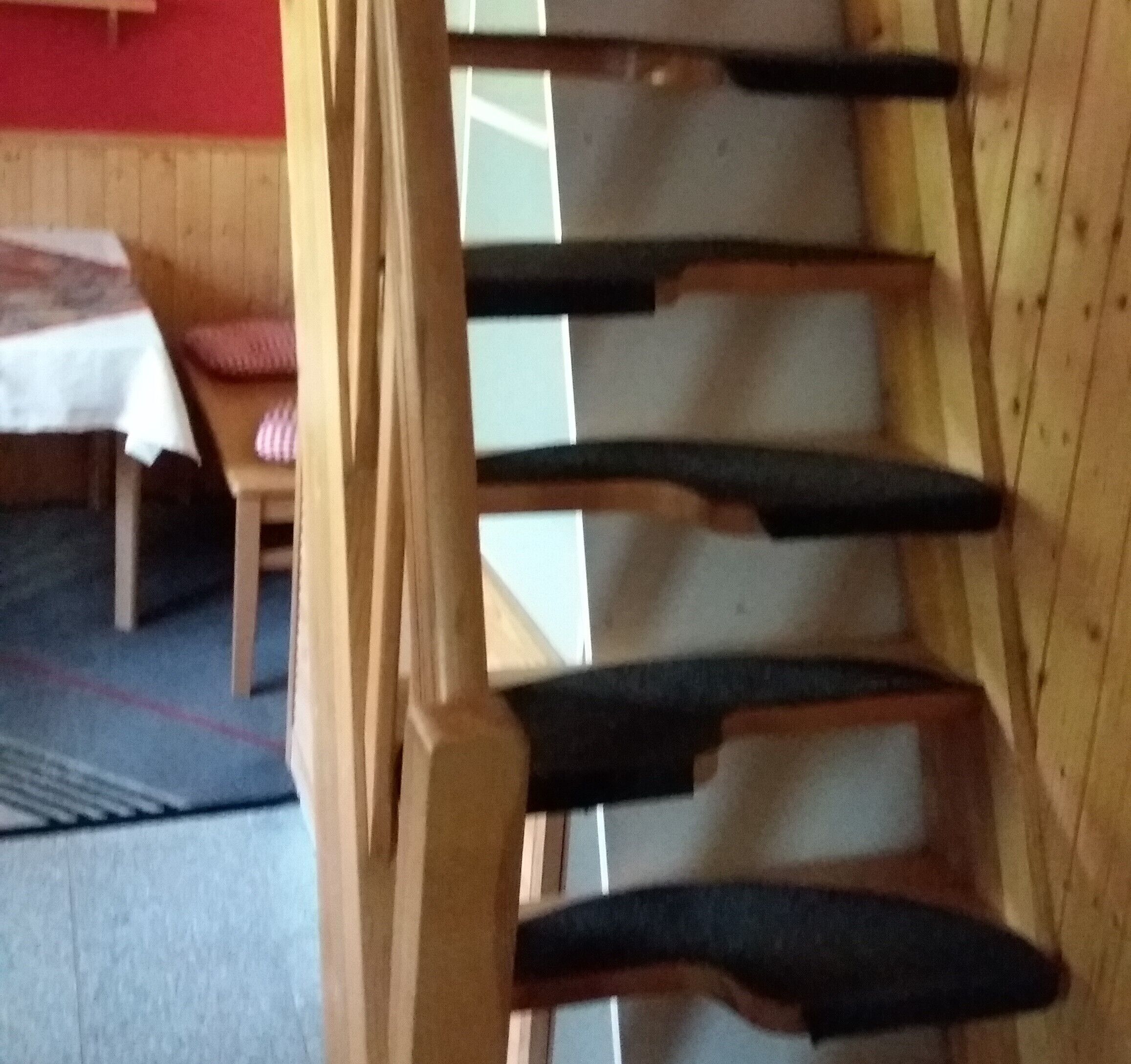 Une pièce avec un banc en bois, une table recouverte d’une nappe blanche et un mur rouge.
