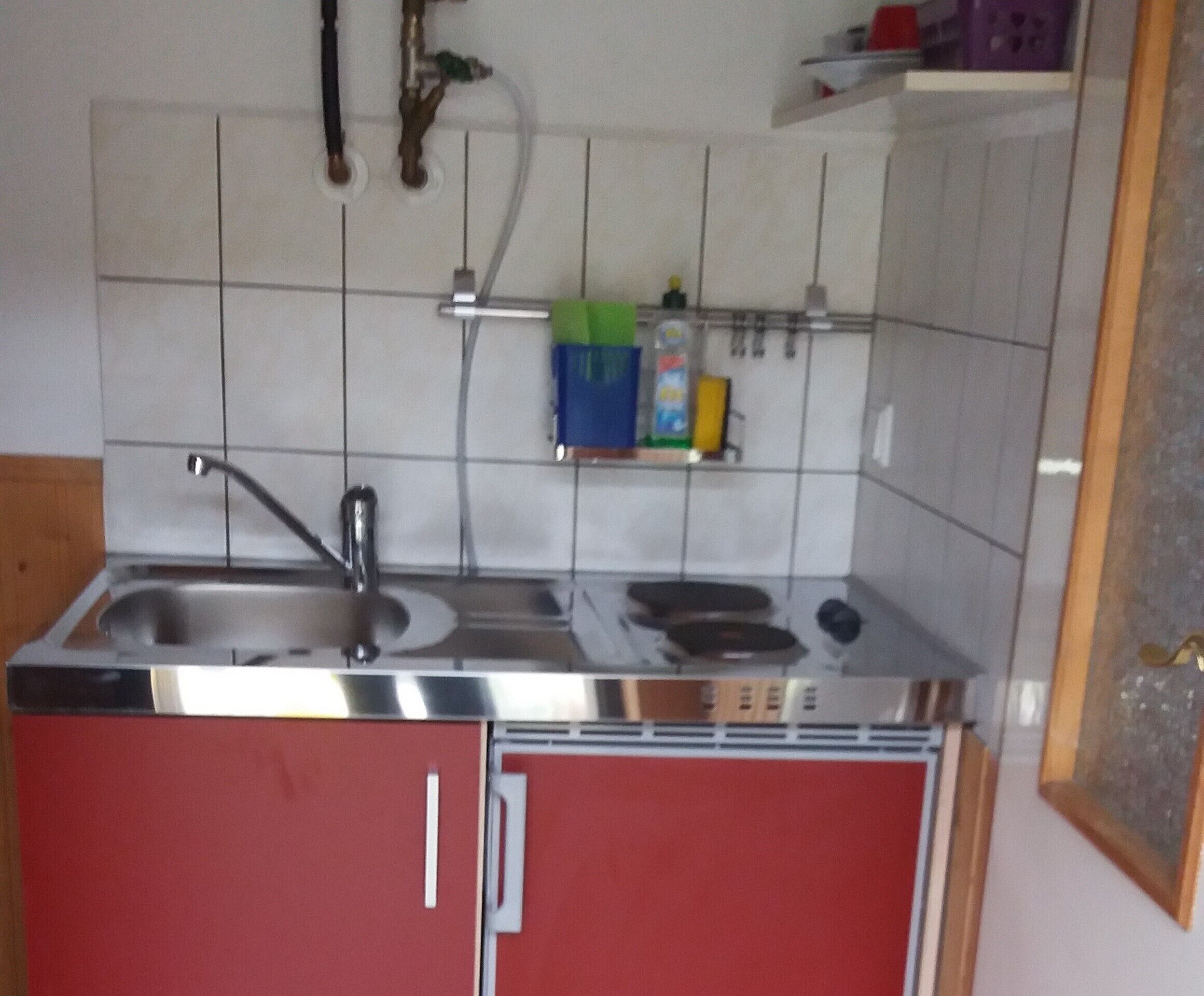 Una cuina compacta amb un rentaplat, fogó i armaris.