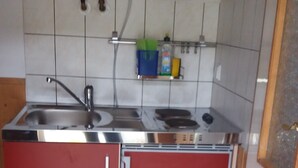 Una cocina compacta con un lavamanos, estufa y alacenas.
