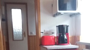 Una cocina con un electrodoméstico rojo, una encimera blanca y una puerta de madera.