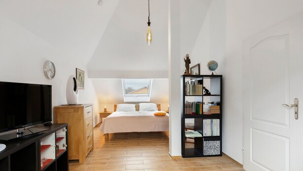 A bedroom with a bed, a TV, a bookshelf, a globe, and a clock.