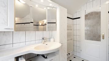 A bathroom with a white sink, mirror, and tiled walls.