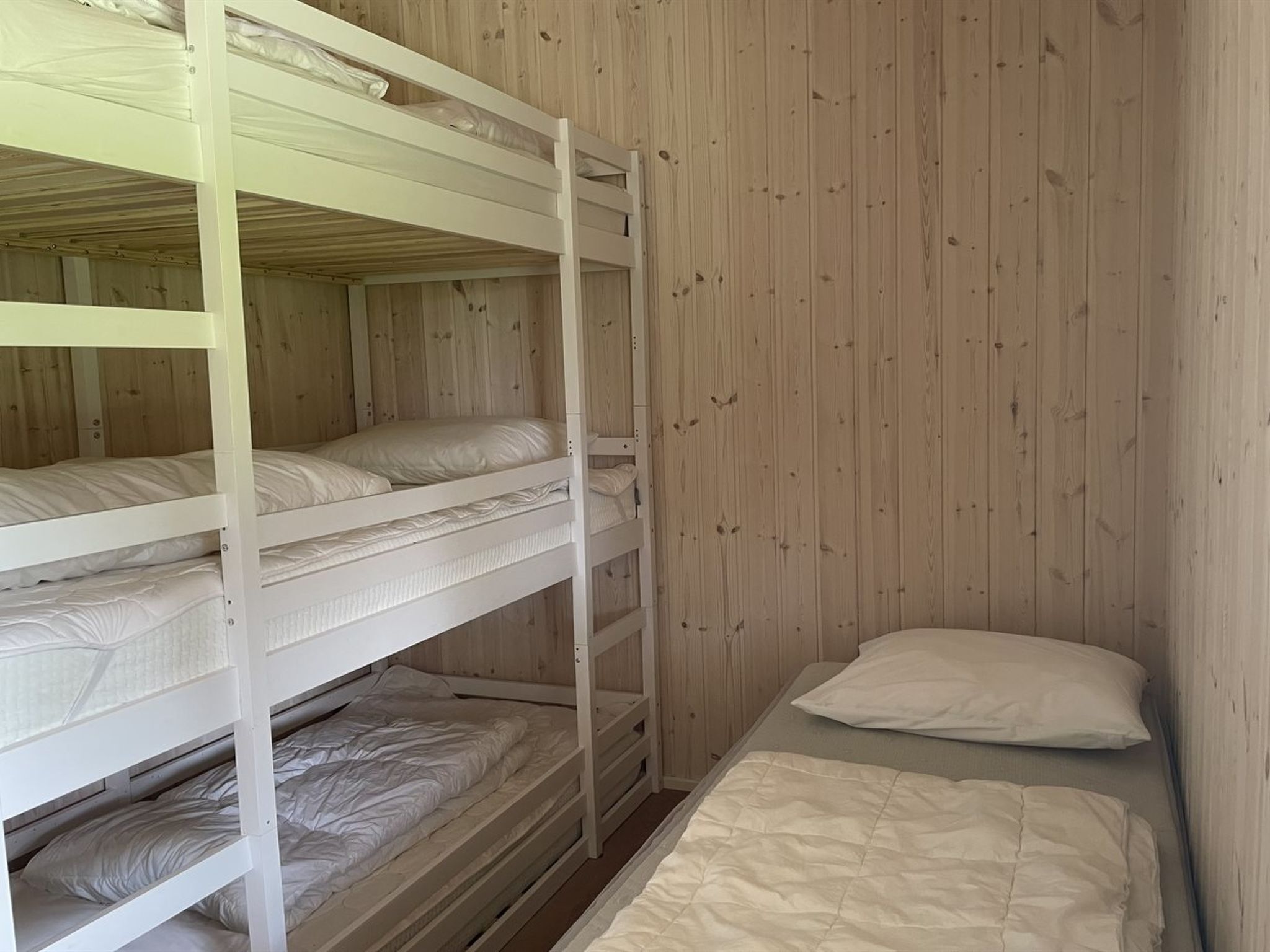 A bunk bed room with wooden walls and a single bed at the bottom.