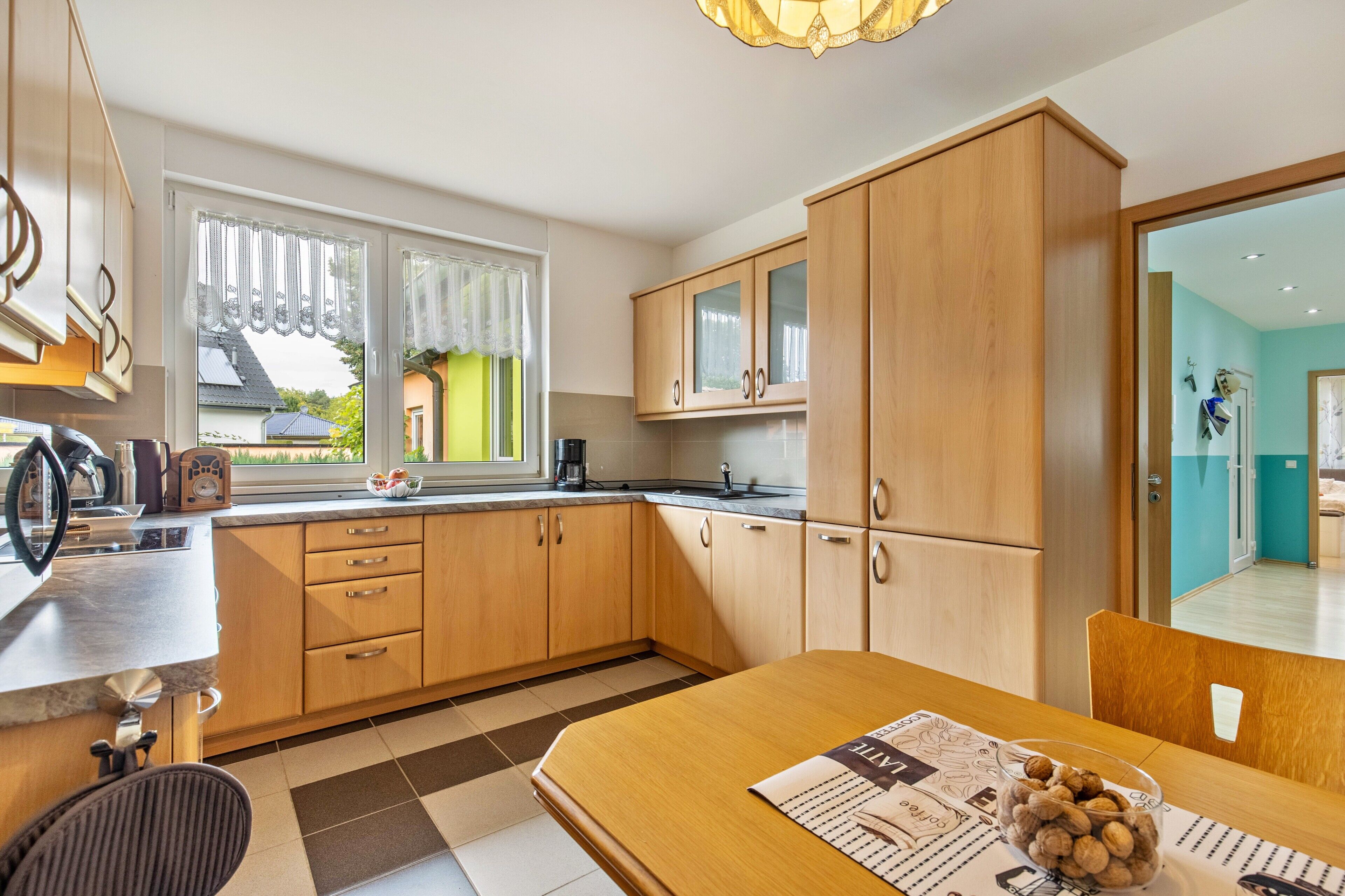 Una cocina moderna con armarios de madera, una mesa de comedor con un periódico y vistas al exterior.