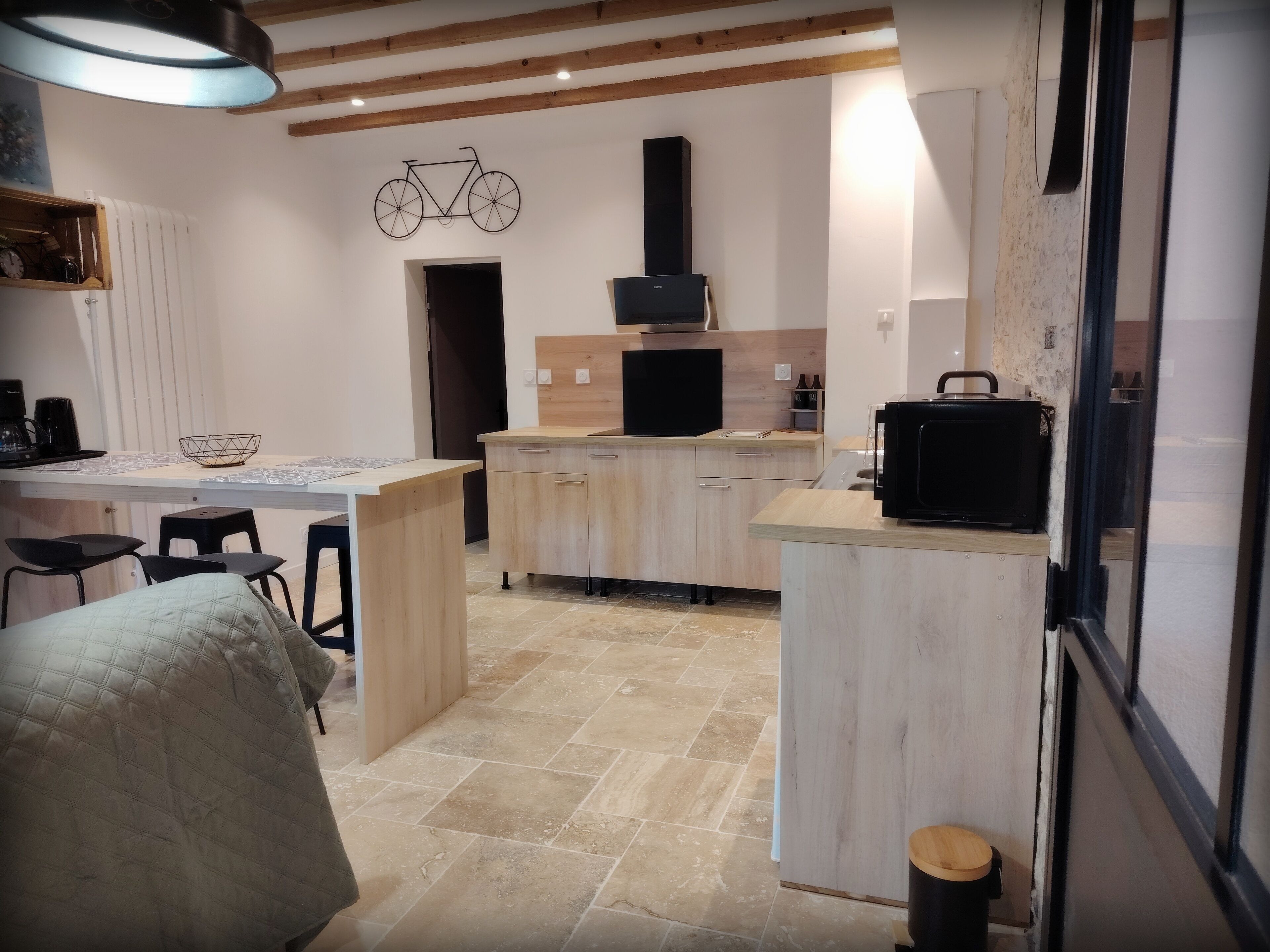 A modern kitchen with a central island, wooden cabinets, and a bicycle decoration on the wall.