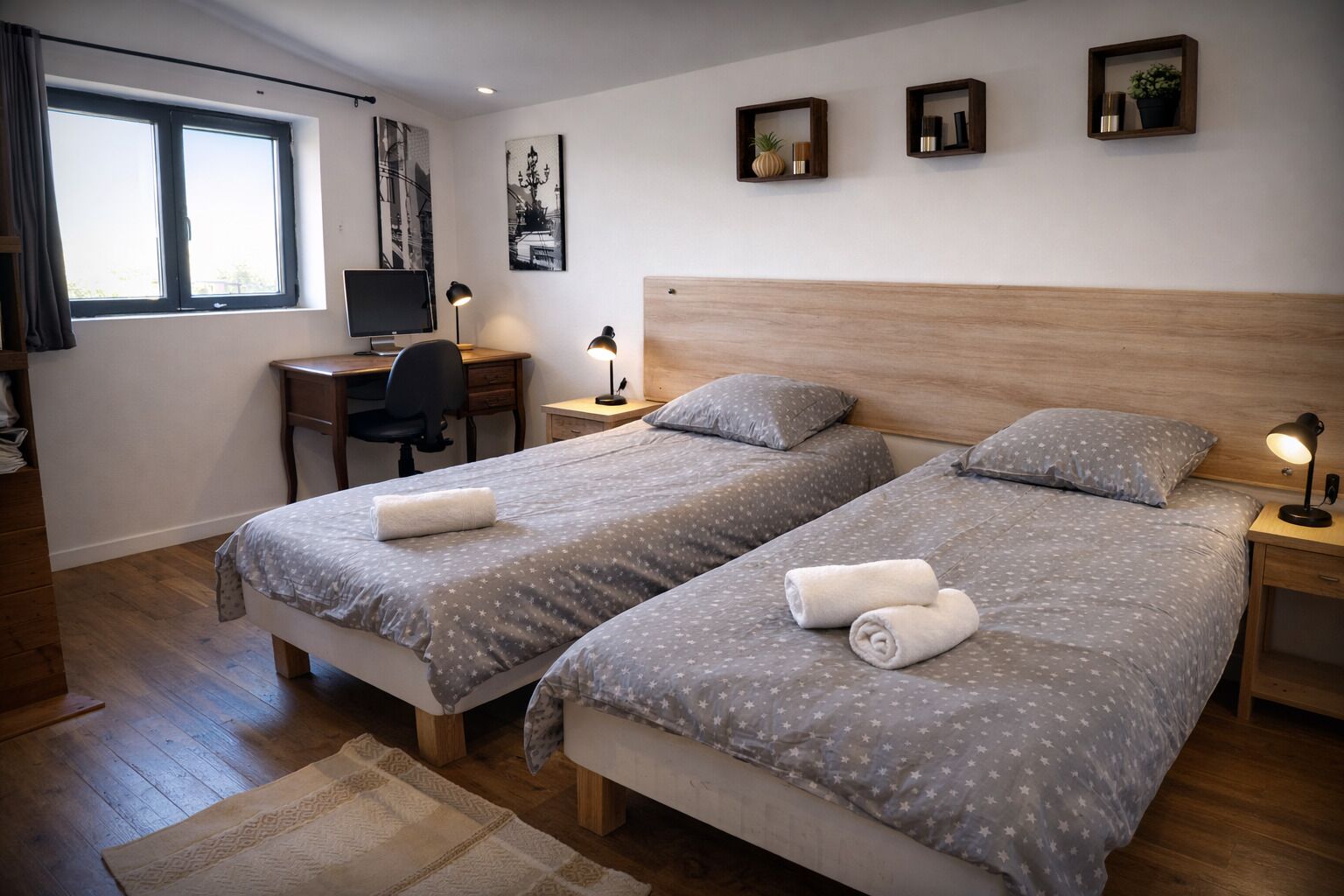 Une chambre d’hôtel avec deux lits, un bureau, une chaise, une télévision et une fenêtre.