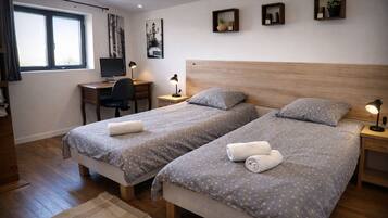 Une chambre d’hôtel avec deux lits, un bureau, une chaise, une télévision et une fenêtre.