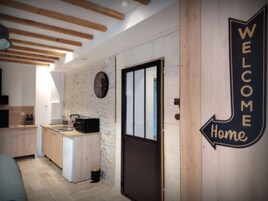 Cozinha moderna com vigas de madeira, um relógio e um letreiro com a mensagem 'WELCOME Home'.