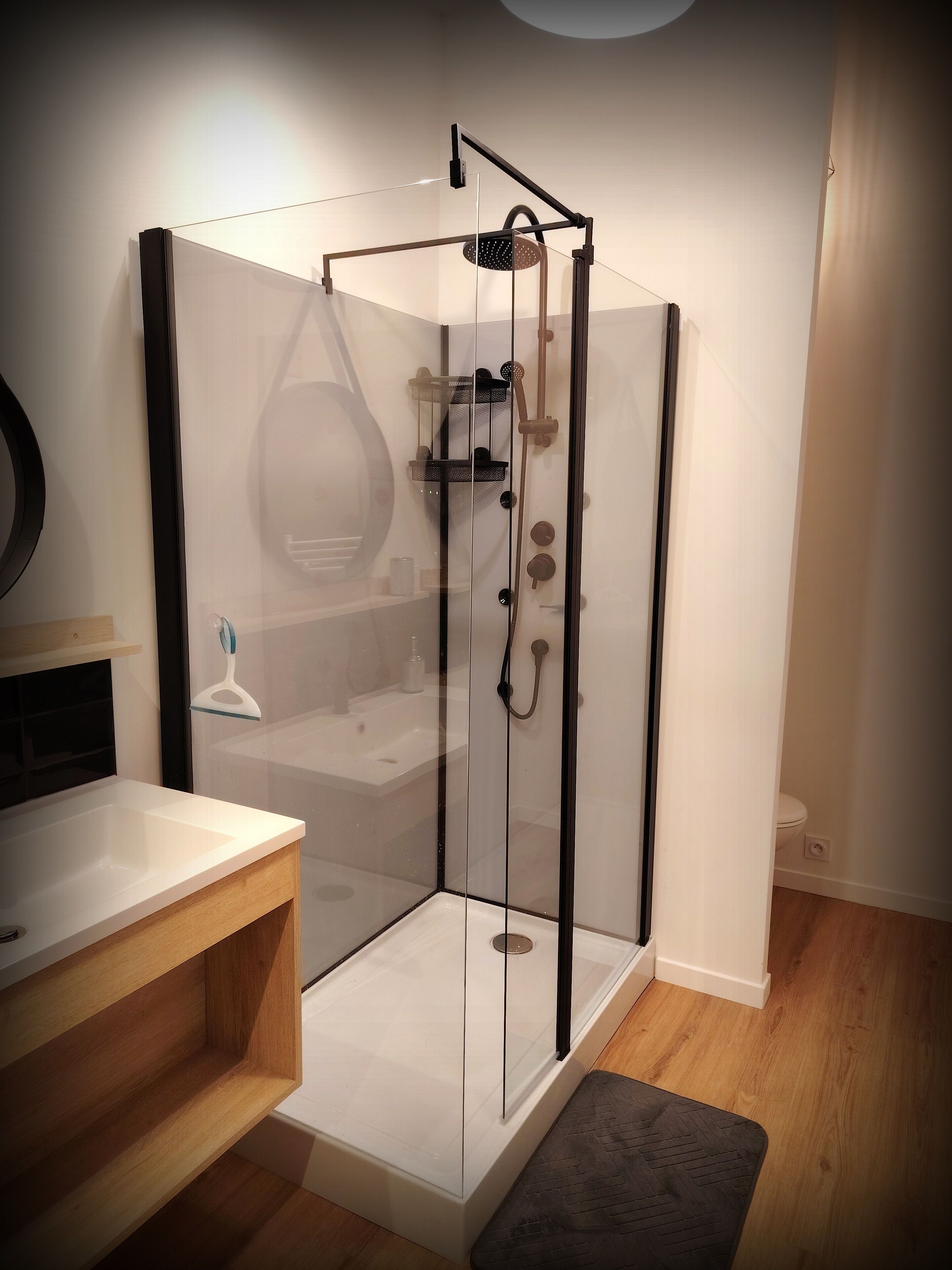 A modern bathroom with a glass-enclosed shower, a wooden vanity, and a white sink.