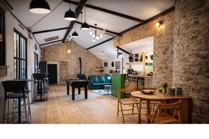 Um amplo loft com paredes de pedra aparente, piso de madeira e uma área de estar acolhedora com mesa de pebolim.