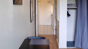 A room with a wooden floor, a blue exercise mat, a painting on the wall, and a door leading to a bathroom. - Résidence hôtelière ERASMUS (Malakoff)