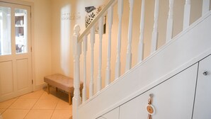 A staircase with white balusters, a bench, and a wall with decorative items. - Skellig Fuchsia Lodge Ballinskelligs (Ballinskelligs)