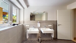 Un baño moderno con dos lavamanos, un espejo y una ventana.