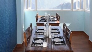 A dining area with a table set for four, large windows with a mountain view, and a blue wall. - the town ville  (Shimla)