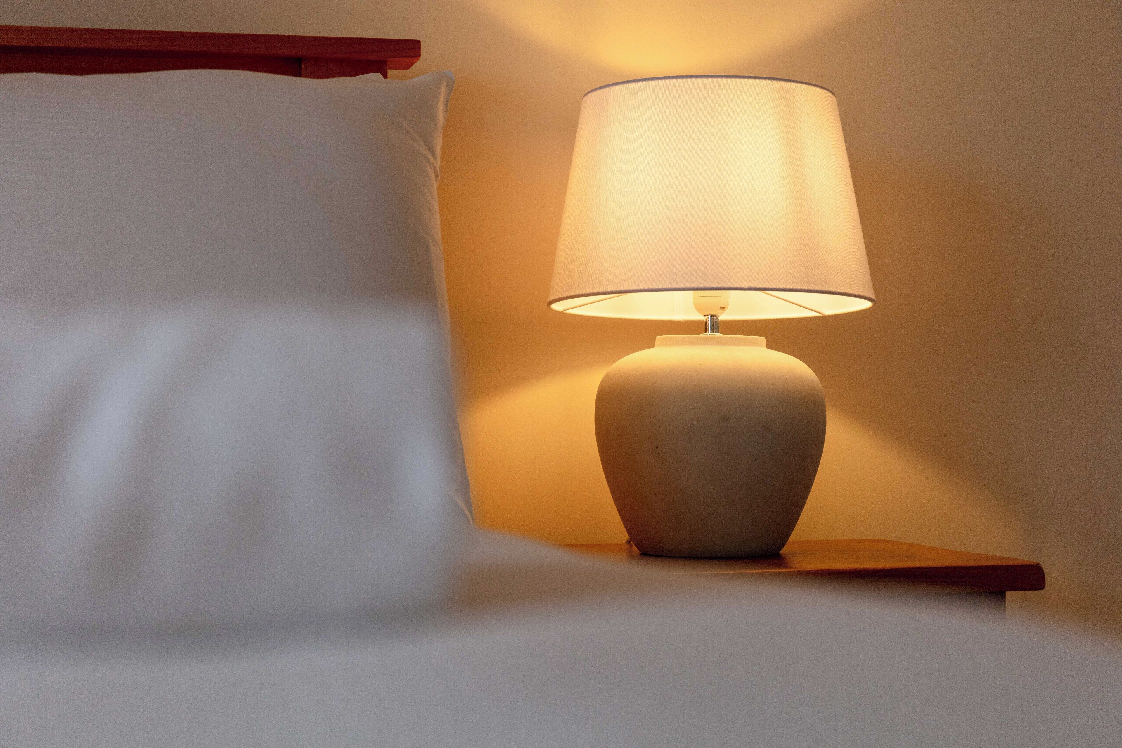 Un lit avec un oreiller blanc et une table de chevet avec une lampe.