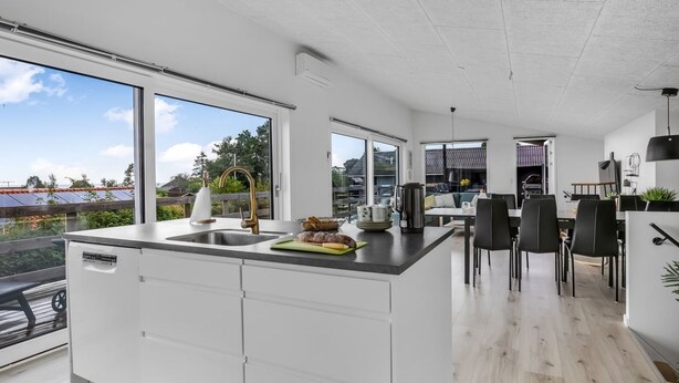 Een moderne keuken met een groot eiland, witte kasten en uitzicht op de buurt.