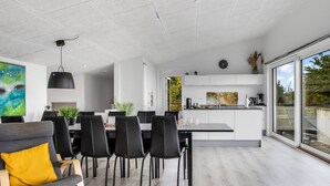 Een moderne keuken met witte kasten, een eethoek met zwarte stoelen en een groot raam met uitzicht op de omgeving.