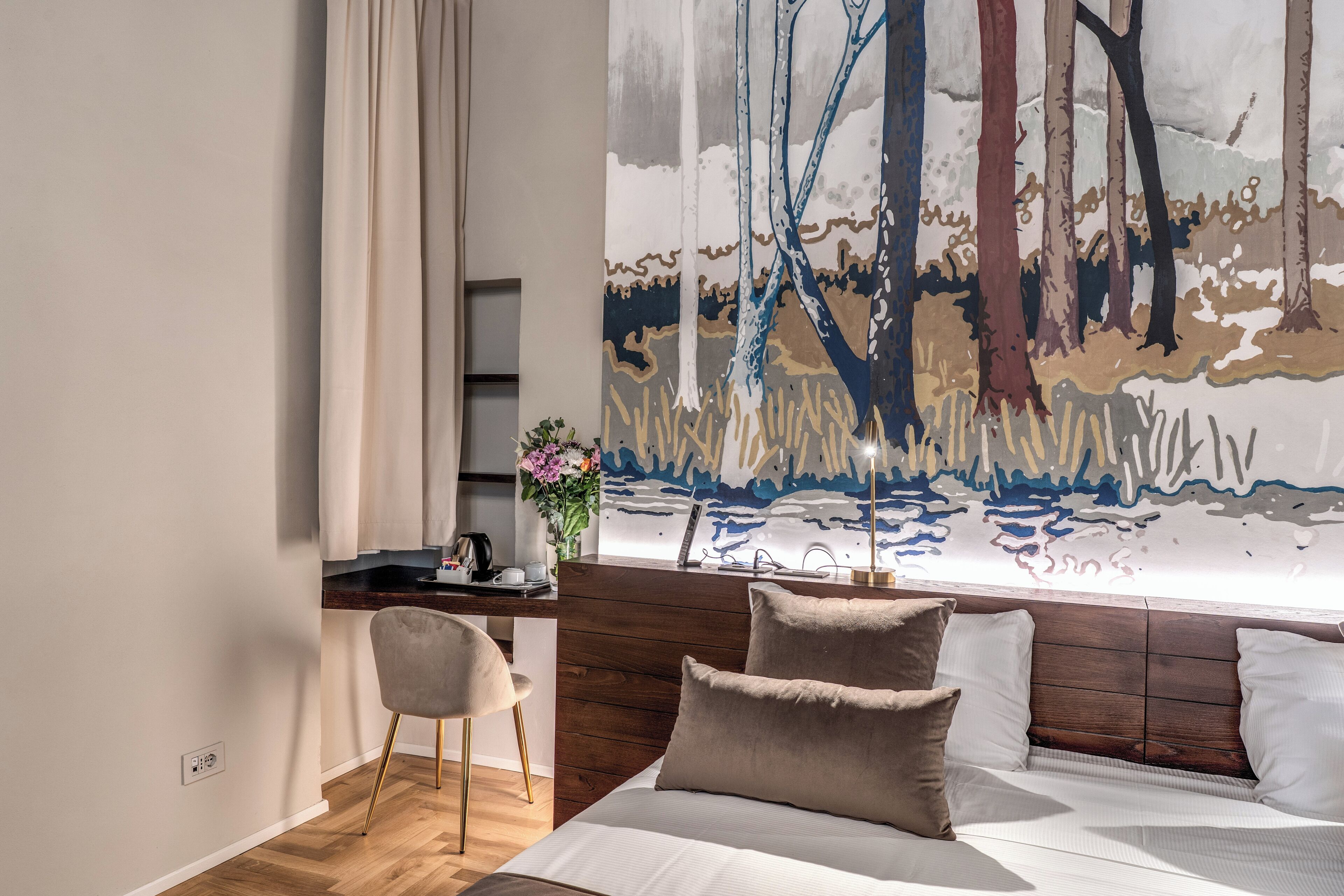 Un dormitorio con cama, escritorio, silla y un cuadro abstracto grande en la pared.