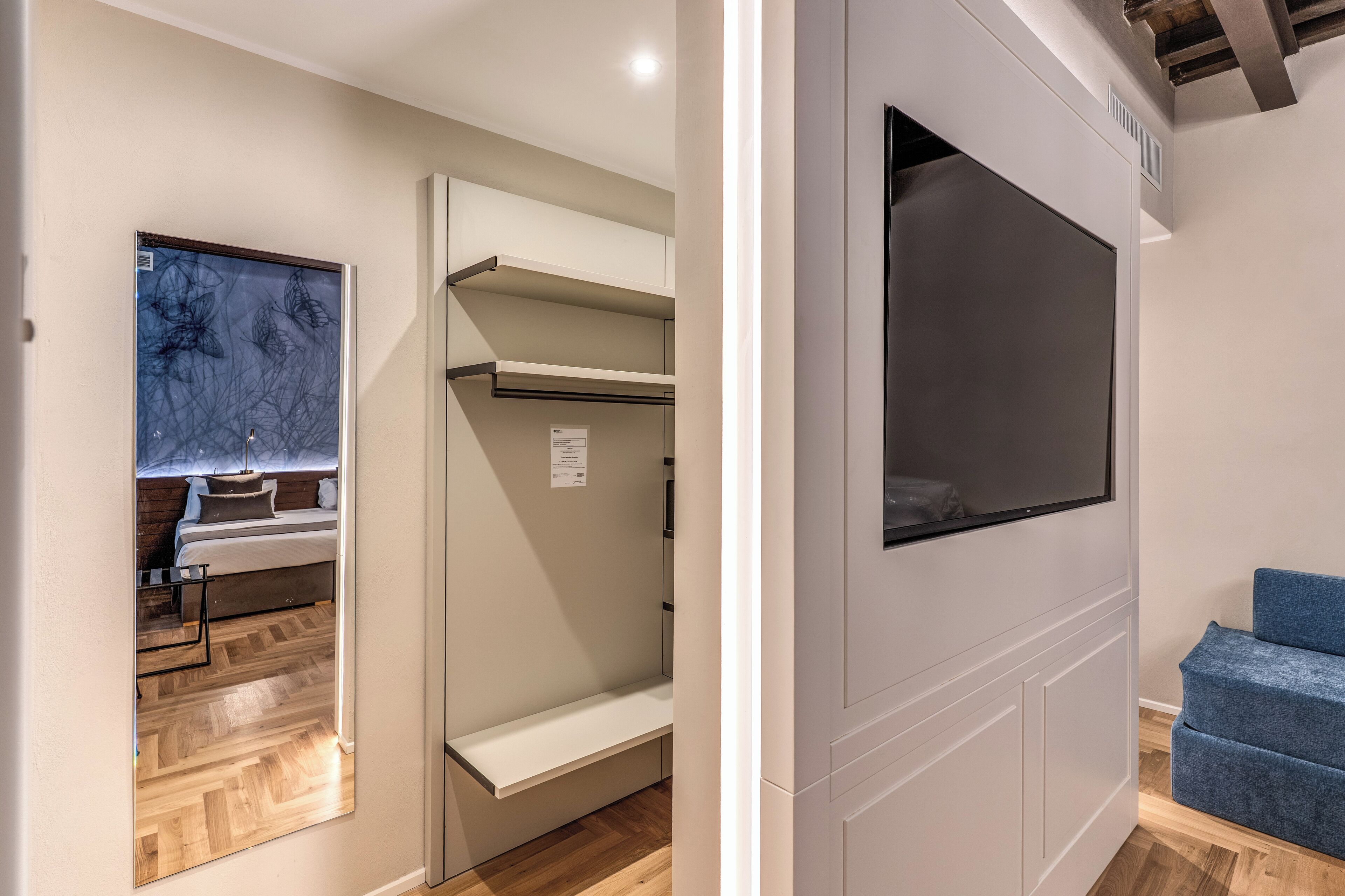 Una habitación moderna con estantes empotrados, una cama con cabecera y un sofá azul.