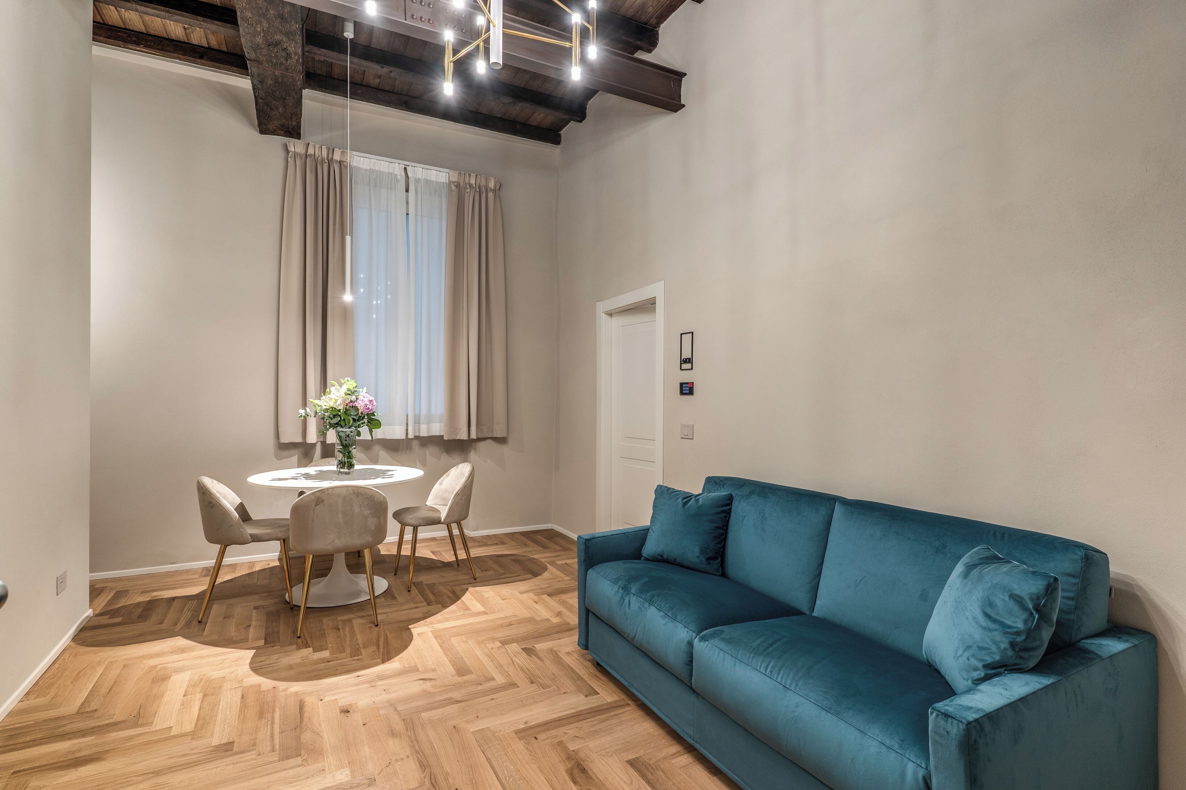 Un saló modern amb un sofà blau, una taula de dinar rodona i caires, i un paviment de fusta en relleu.