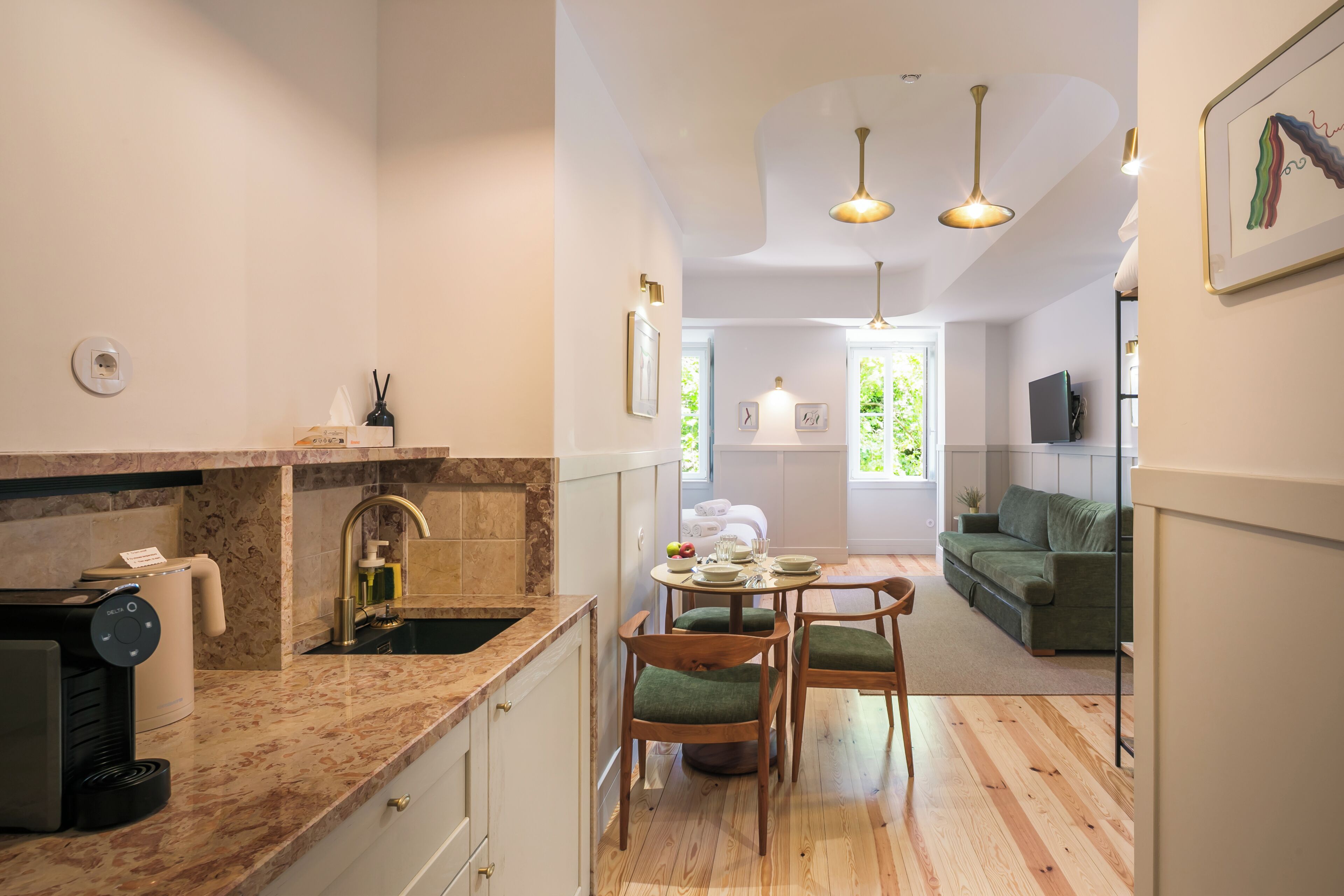 A modern kitchen with a coffee machine, a sink, and a dining area with a table and chairs.