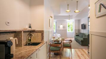 A modern kitchen with a coffee machine, a sink, and a dining area with a table and chairs.