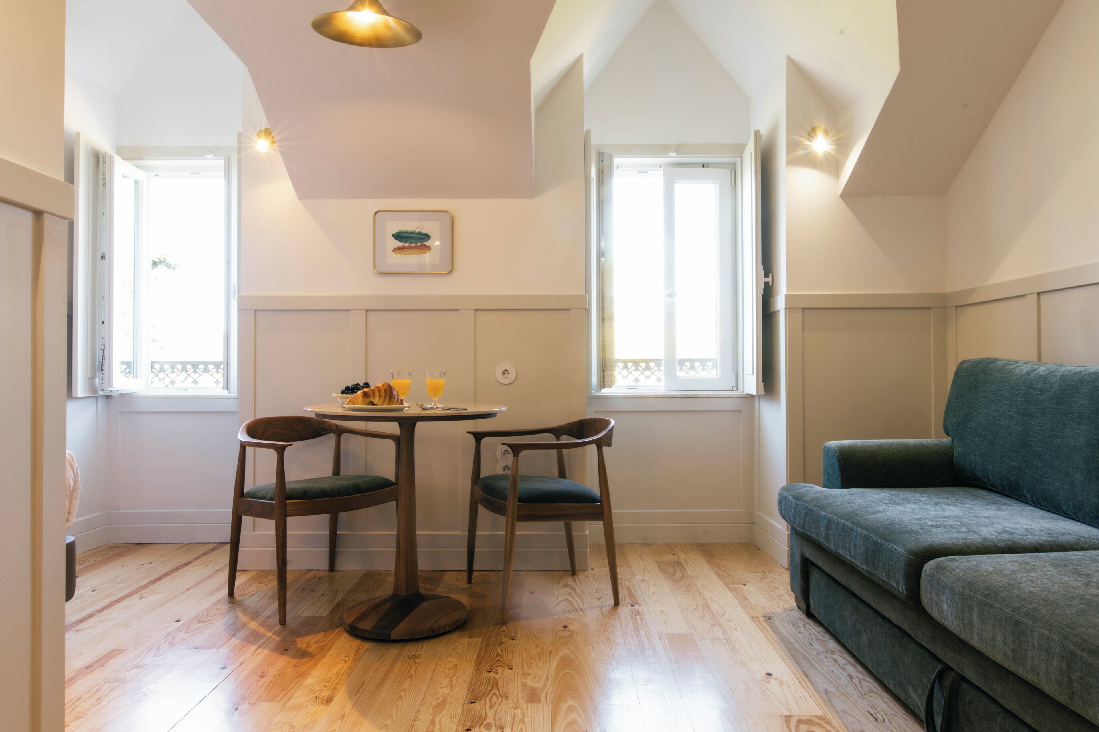 Una habitación con una mesa de comedor, dos sillas, un sofá y una ventana con vistas.