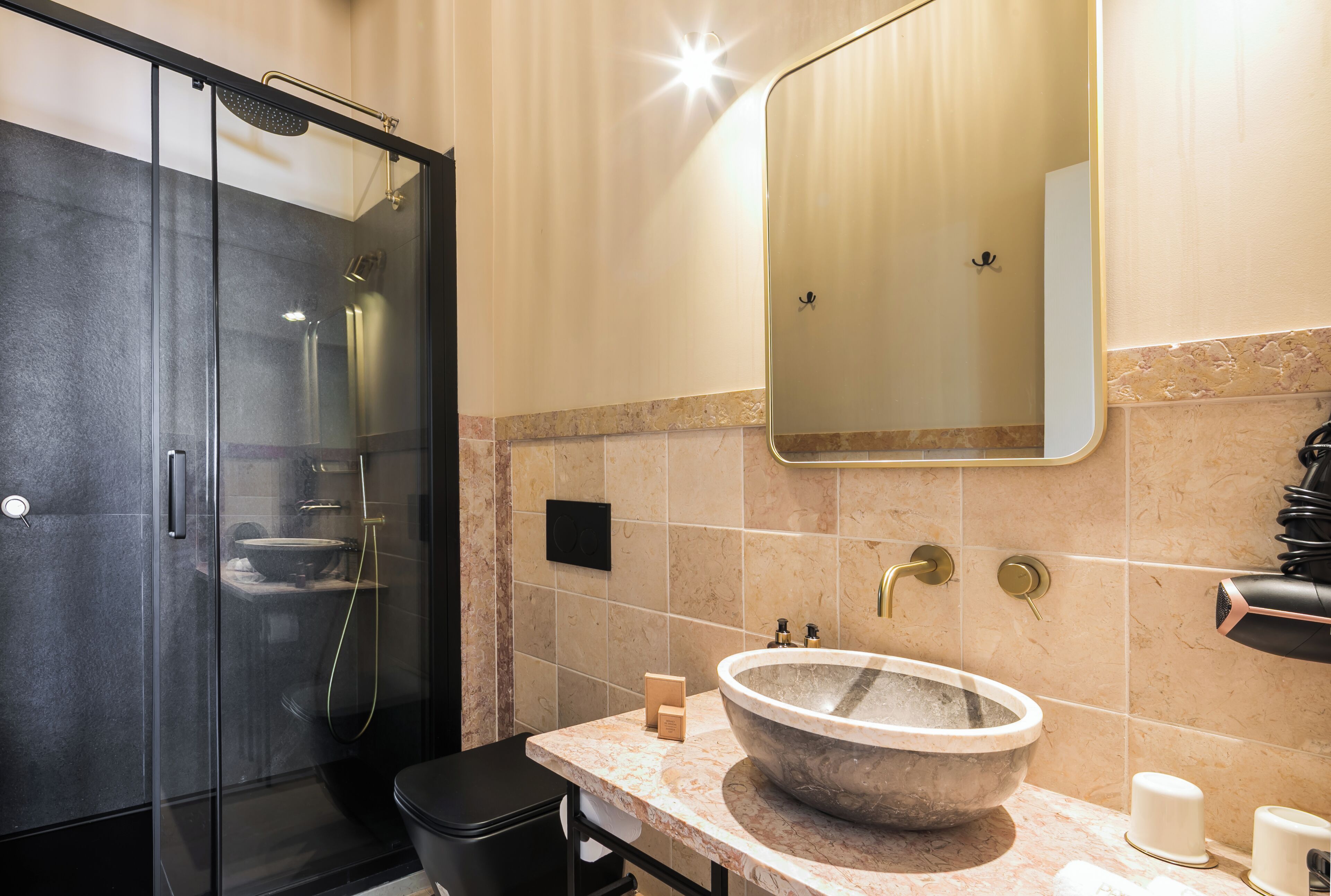 Un baño moderno con ducha de vidrio, un lavamanos grande de mármol y un espejo sobre el lavamanos.