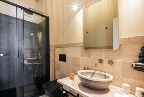 Un baño moderno con ducha de vidrio, un lavamanos grande de mármol y un espejo sobre el lavamanos.