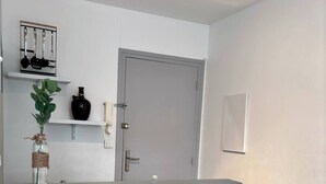 A modern kitchen with a grey countertop, white walls, and a wooden floor. - Charming apartment in Arras for a cozy getaway (Arras)