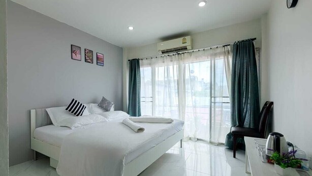 Habitación de hotel con cama, escritorio con cafetera y ventana con cortinas.