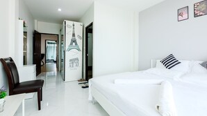 Habitación de hotel moderna con una cama grande, un escritorio y una silla. Se observa una puerta con un mural decorativo de la Torre Eiffel.