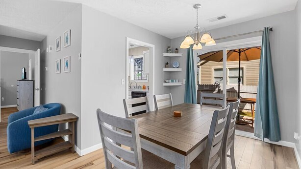 Un comedor con una mesa y sillas de madera, un sofá azul y una cocina al fondo.