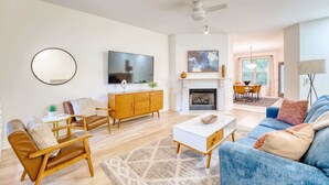 A modern living room with a fireplace, a television, and a dining area.