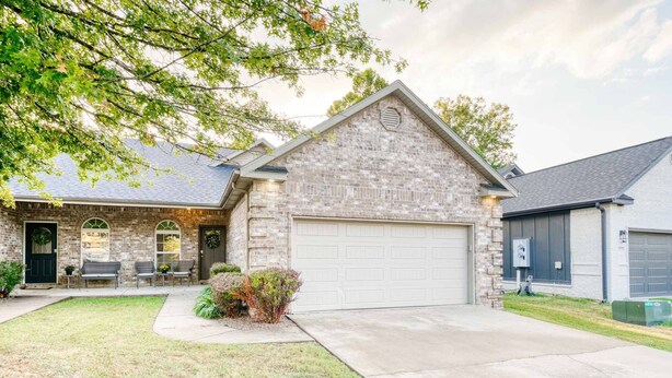 A two-story house with a stone facade, a garage, and a front porch with wicker furniture.