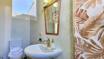 A bathroom with a white sink, a mirror, and a toilet.