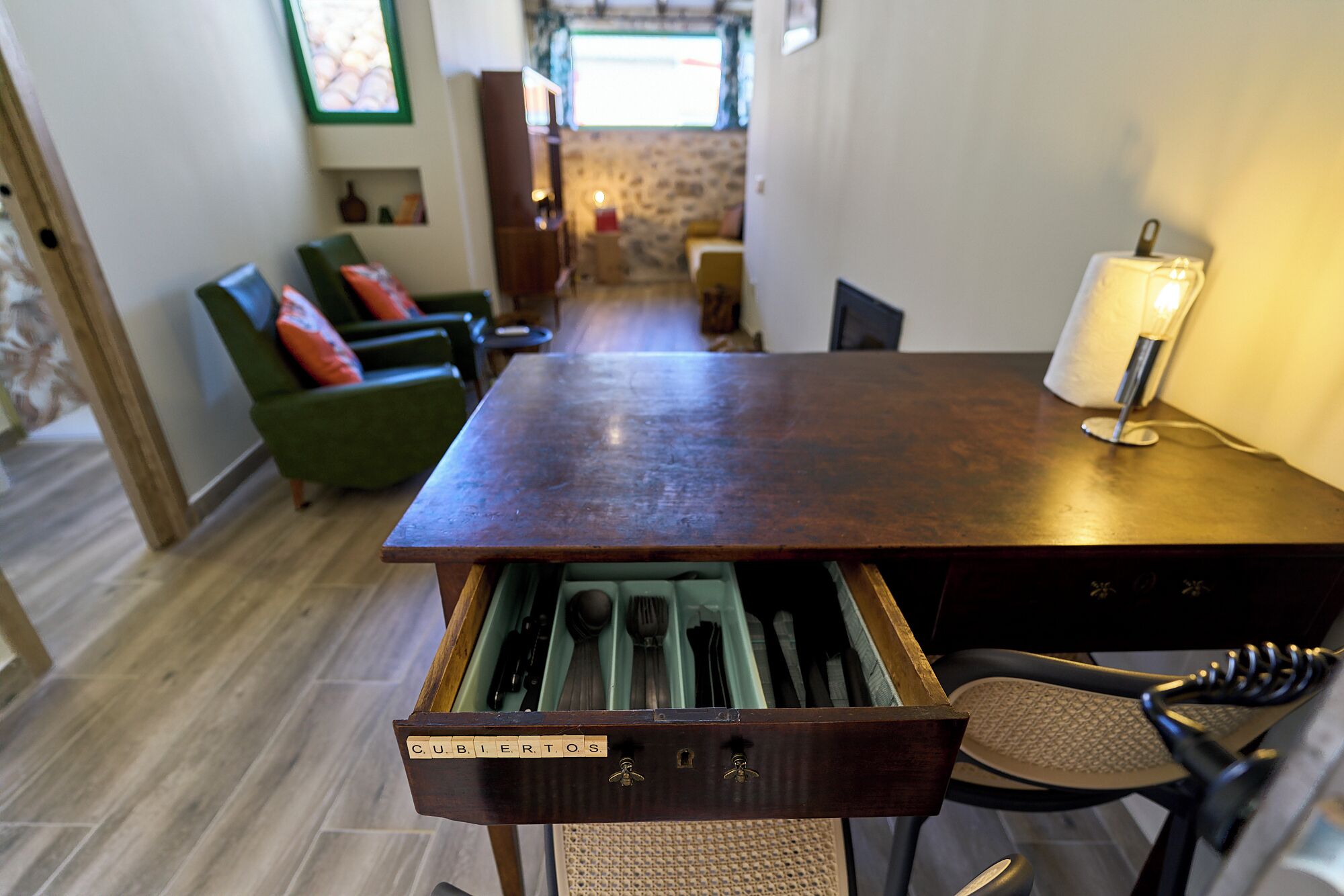 A wooden dining table with a drawer containing cutlery.