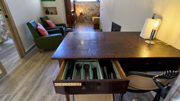 A wooden dining table with a drawer containing cutlery.