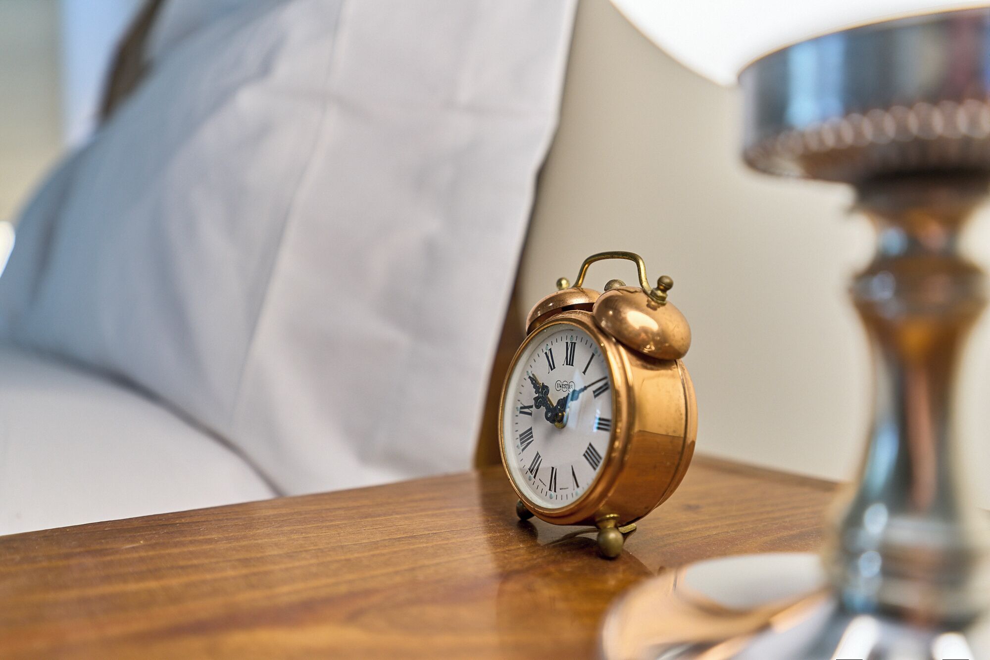 A gold alarm clock on a wooden surface.