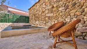 Eine Steinsäule, ein kleiner Pool und Korbstühle im Freien.