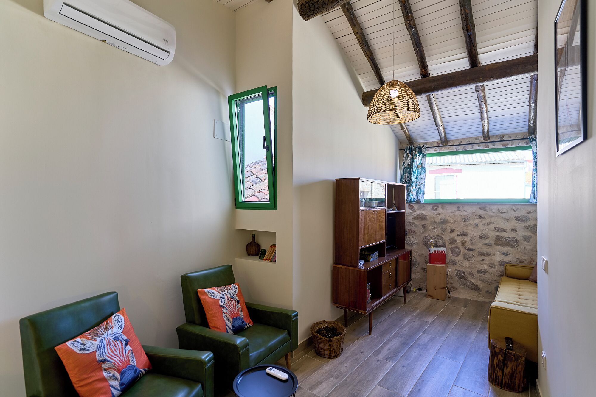 A cozy room with green leather chairs, a wooden cabinet, and a woven light fixture.