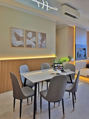 A modern dining area with a white table, grey chairs, and abstract wall art.