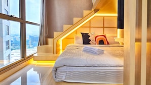 Un dormitorio moderno con un ventanal grande, una cama con almohadas y un televisor.