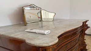 Una encimera de mármol con un mando a distancia y un espejo.