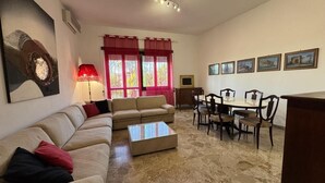 Una sala de estar con un sofá, una mesa de centro, una mesa de comedor con sillas y un televisor.